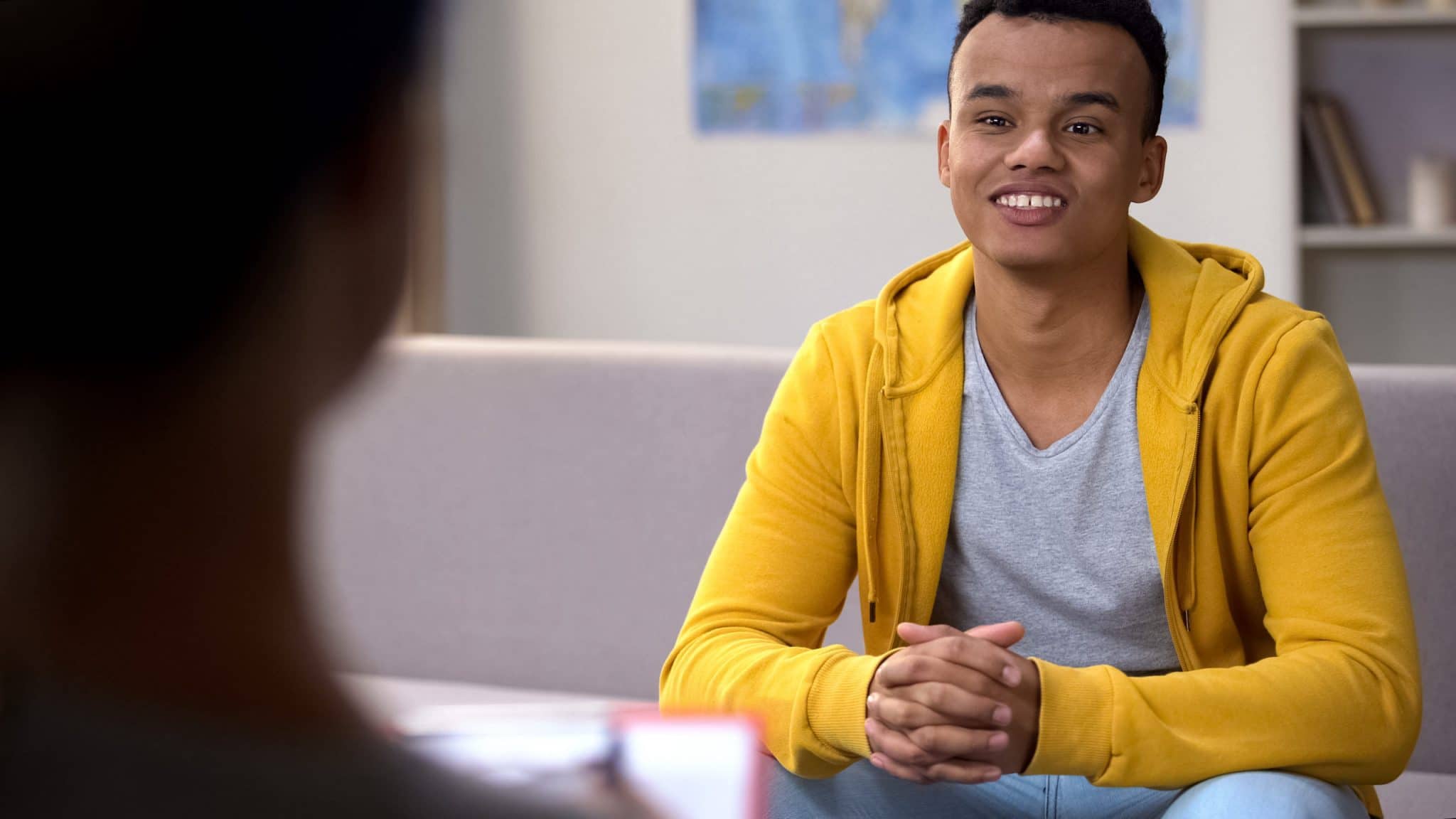 Ethnic teenager visiting psychotherapist and smiling