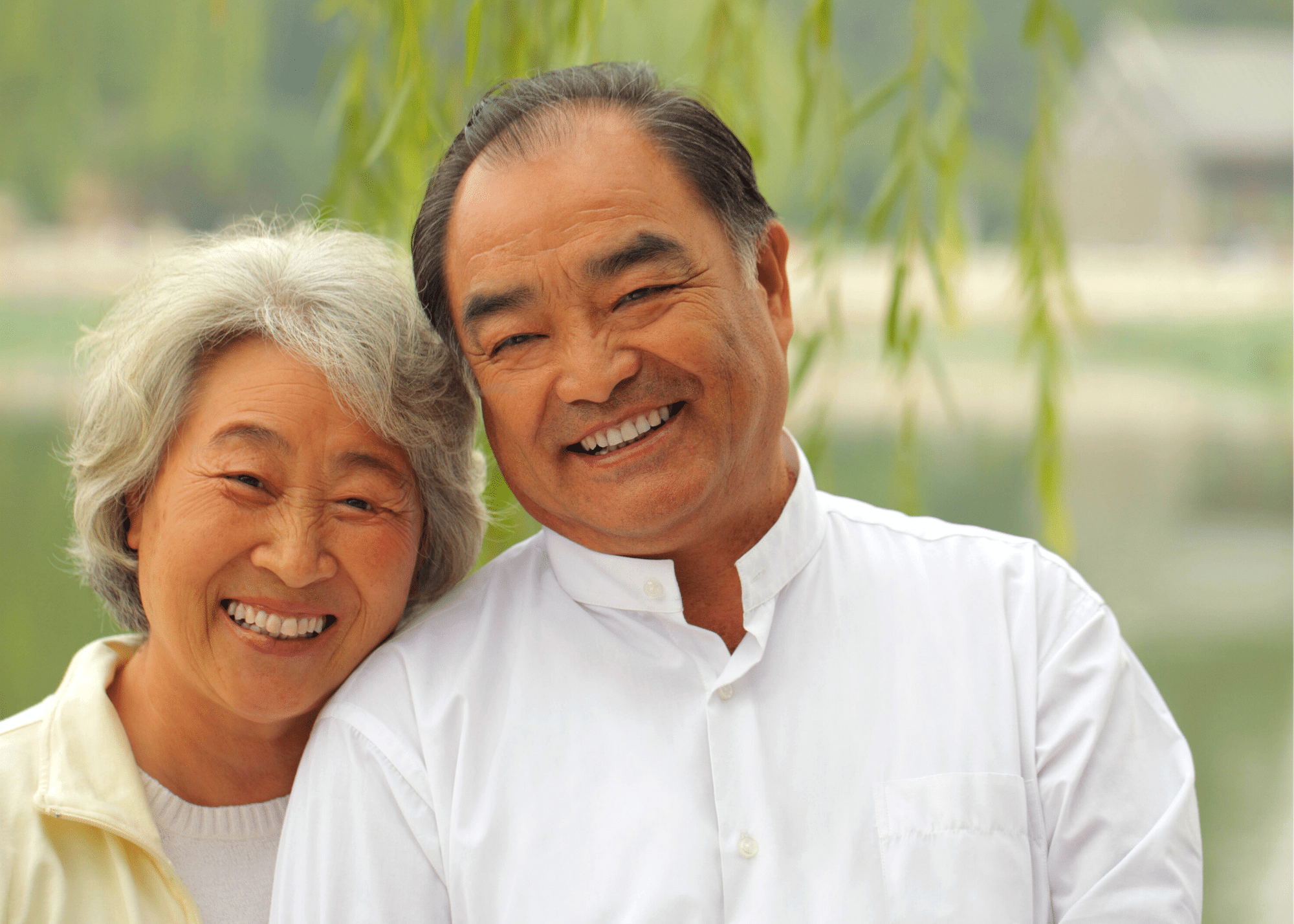 Portrait of an older Asian couple smiling and looking at the camera while outside